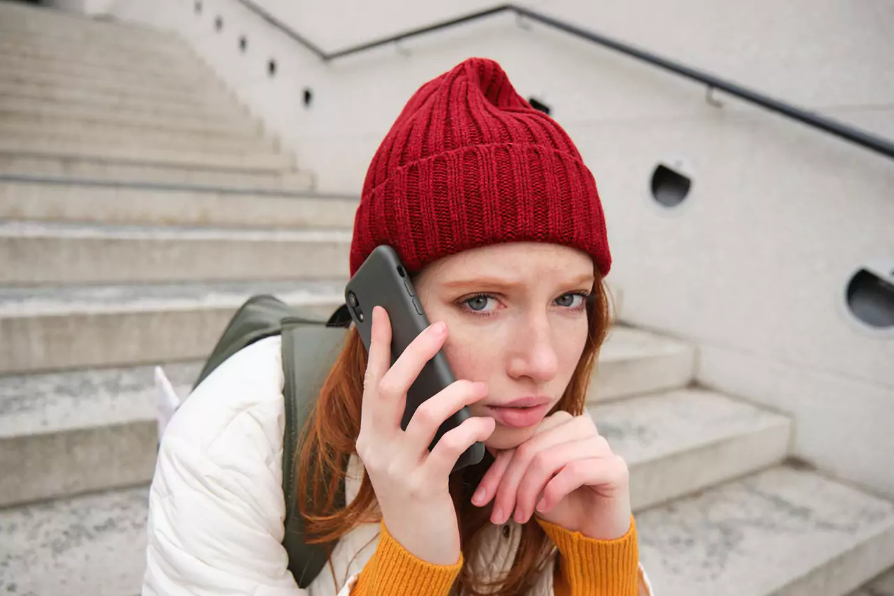 rodharig tjej med bekymrat ansikte ser orolig ut medan samtal pratar i telefon