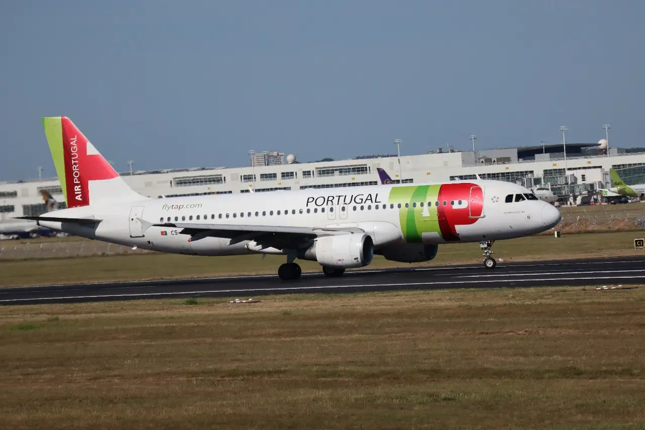 A TAP plane on the runway during the day preparing for take-off.