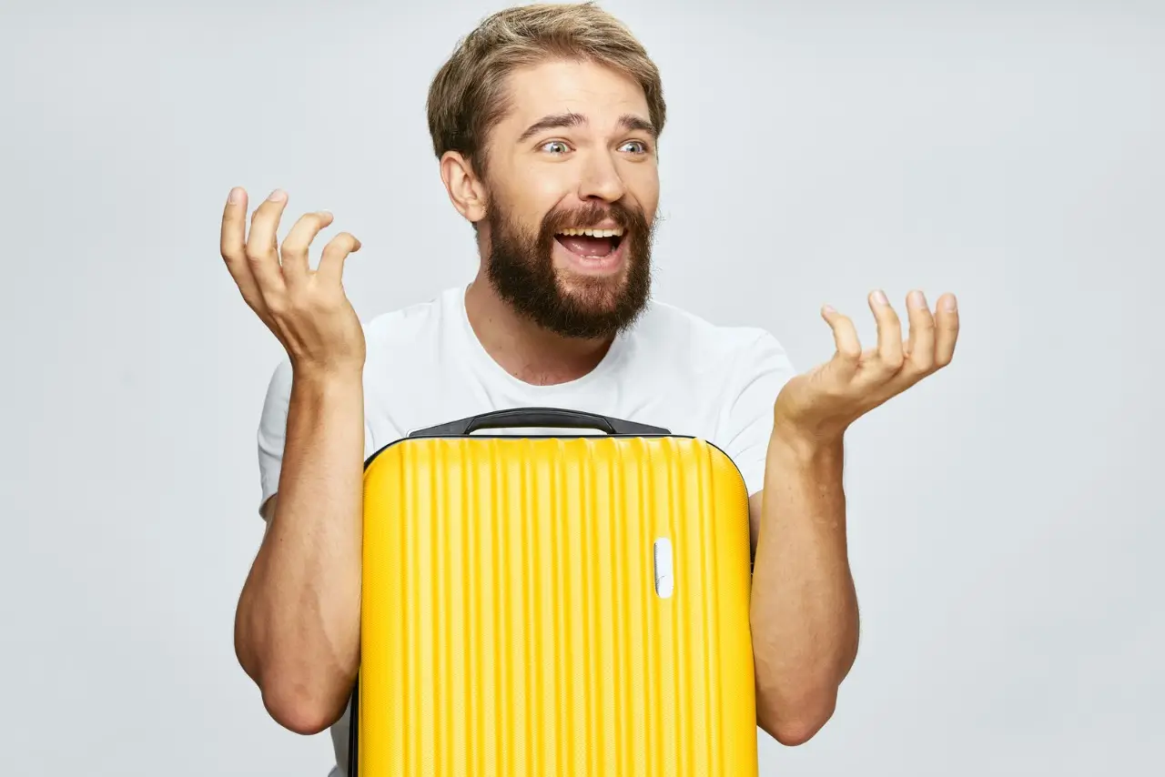 un homme souriant avec une valise jaune