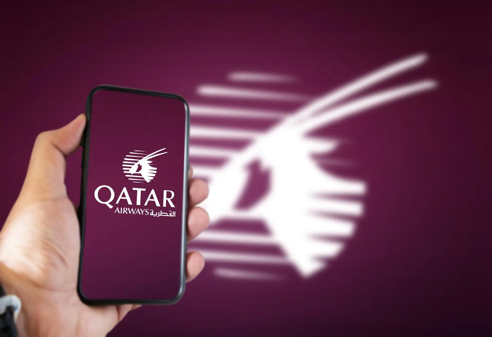 una mano che tiene un telefono con l'immagine di qatar airways