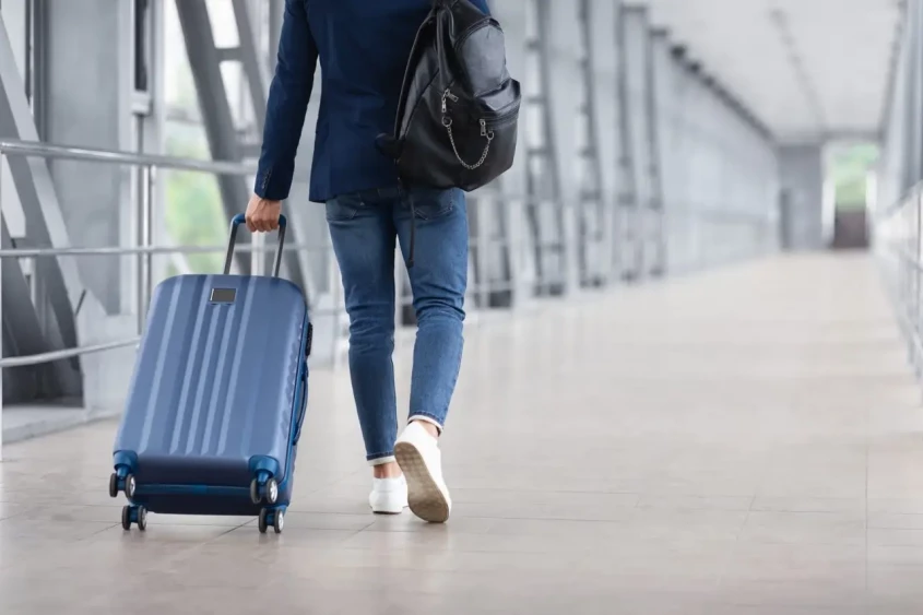 un homme marche dans un a&eacute;roport avec sa valise