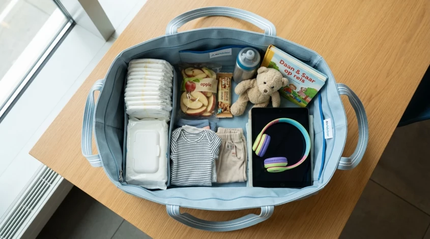 Ingepakte handbagage met luiers, snacks, kleding en speelgoed voor een kind