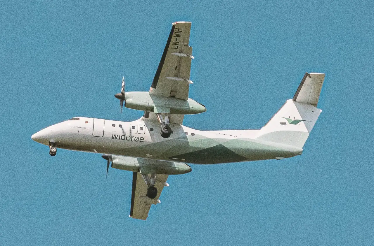 A Widerøe prop plane flying in a blue sky