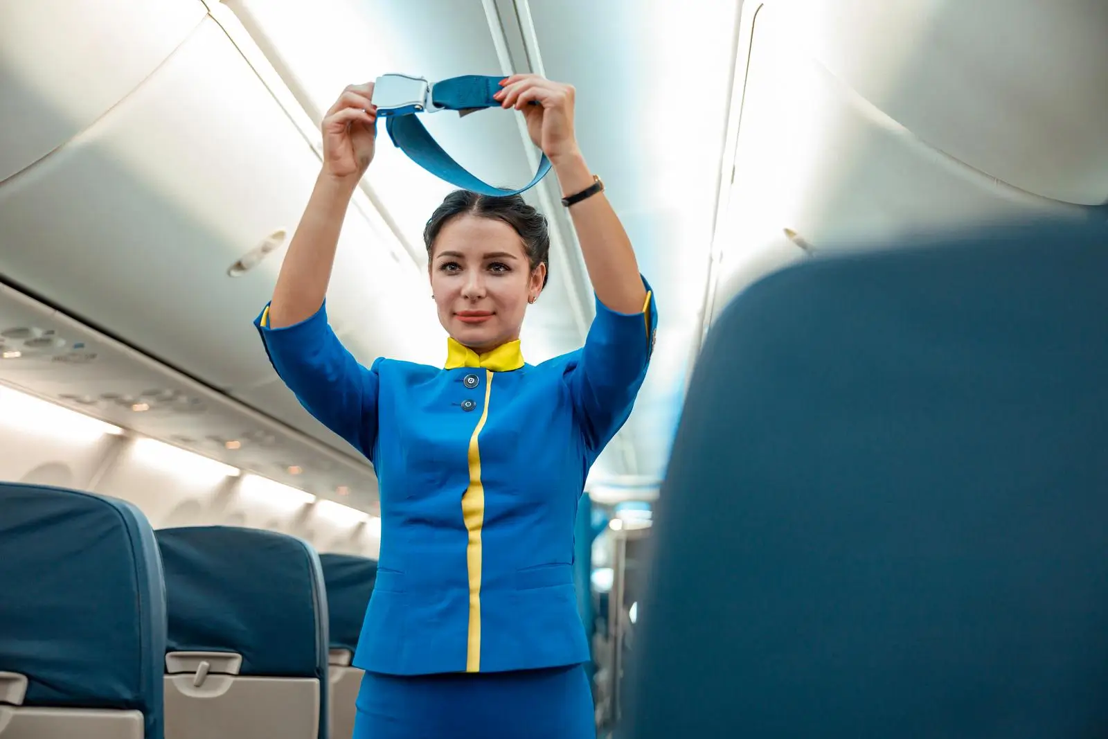 woman stewardess demonstrating how to use safety belt in aircraft