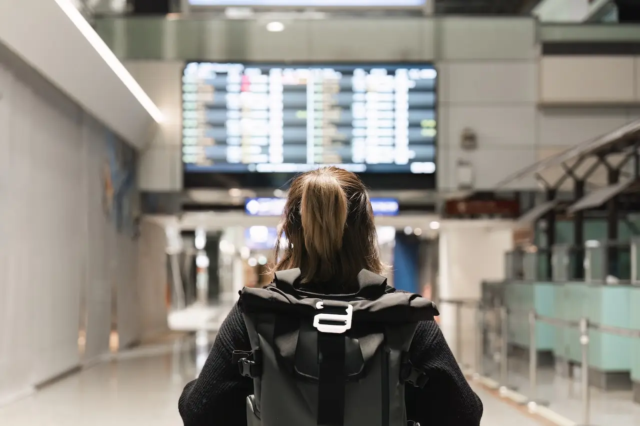 A woman consults the board for Alaska Airlines cancellations