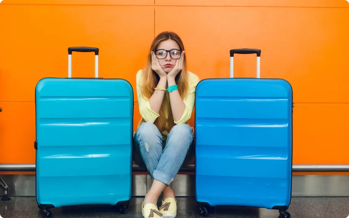 une femme triste assise a coté de ses valises