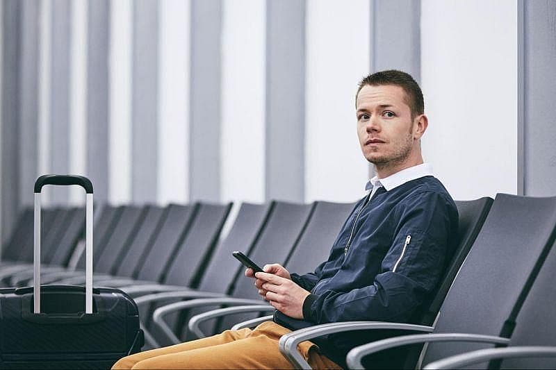 Genrebild &ouml;ver en resen&auml;r som v&auml;ntar p&aring; sin avg&aring;ng medan han anv&auml;nder sin smartphone.