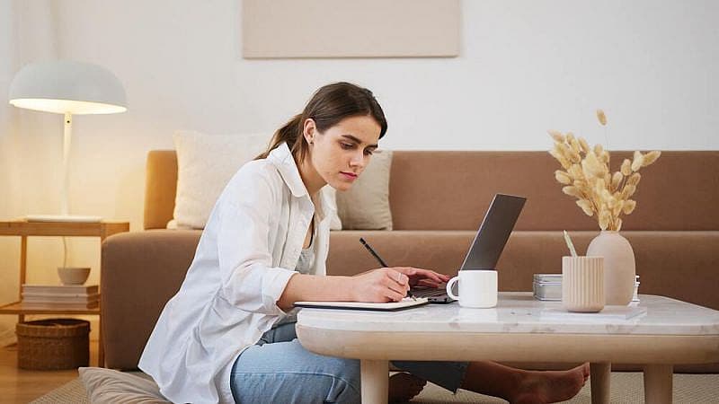 Ragazza seduta a un tavolo che scrive davanti a un PC