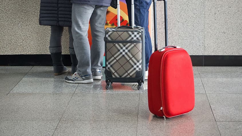 Roter Koffer steht am Flughafen