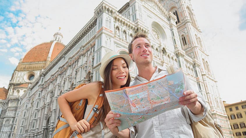 Pareja de turistas con mochila y mapa delante de la catedral de Florencia