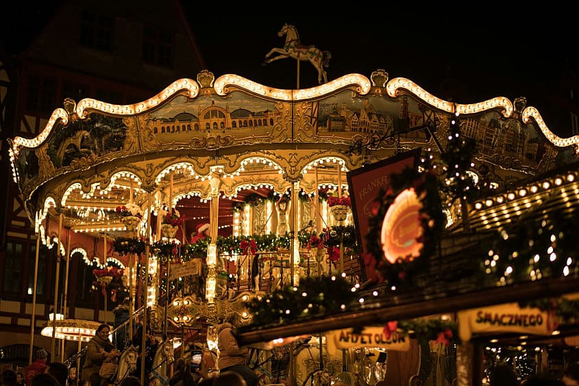 T&acirc;rg de Crăciun &icirc;ntr-un oraș european, cu tarabe și lumini festive
