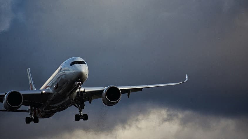 Plane flying under dark storm clouds
