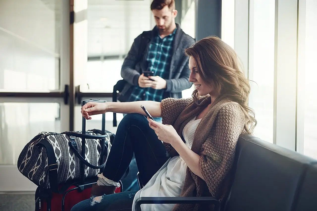 Passengers at airport using smartphone to request a flight refund online