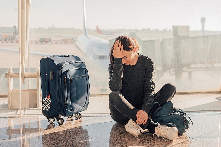 Una pasajera espera sentada en el suelo tras la cancelaci&oacute;n de su vuelo en el aeropuerto de Alicante