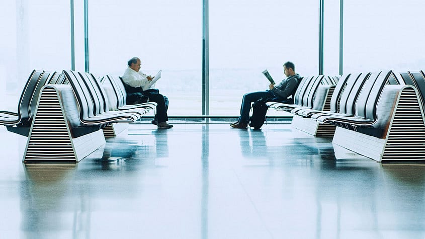 Dos pasajeros sentados esperando su vuelo en el aeropuerto de Ibiza