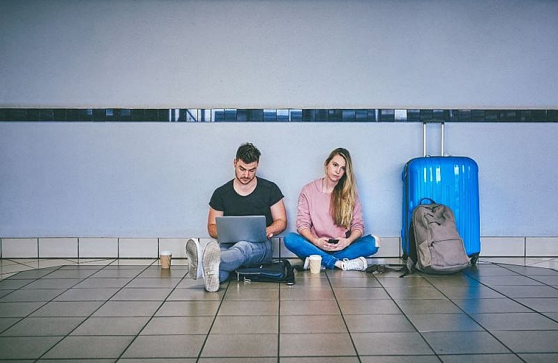 Due ragazzi seduti sul pavimento dell'aeroporto mentre aspettano il loro volo Wizz Air in ritardo