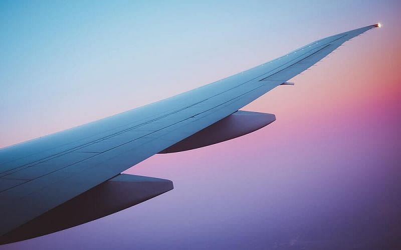 Ala di un aereo nel cielo con sfumature rosse e viola