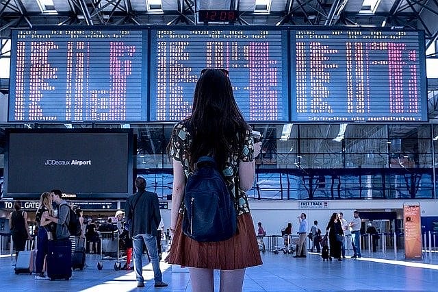Frau blickt auf Abflugtafel am Flughafen