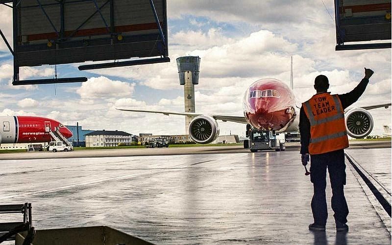 Genrebild p&aring; flygplatspersonal som dirigerar ett Norwegian flygplan p&aring; marken