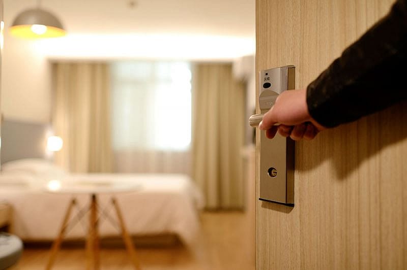 Person &ouml;ffnet T&uuml;re zu einem Hotelzimmer