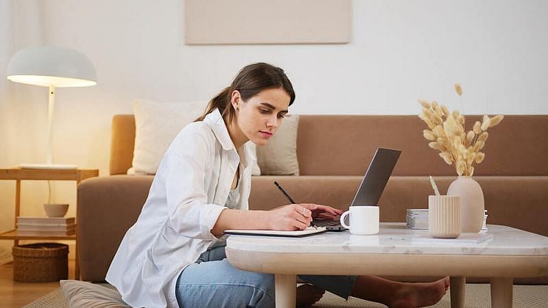 Ragazza seduta a un tavolo che scrive davanti a un PC