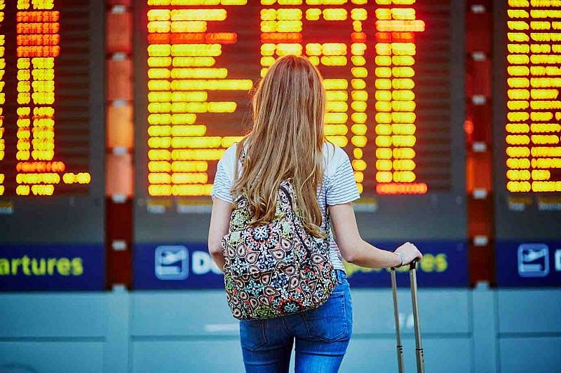 a woman standing in the airport looking at information board
