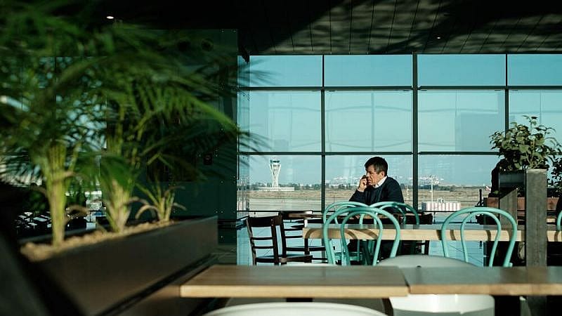 Uomo al telefono seduto a un tavolo in aeroporto
