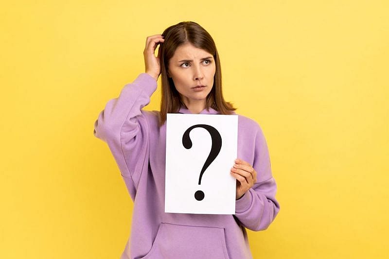 a woman holding a piece of paper with a question sign on it
