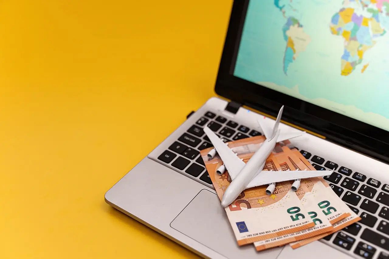 notas en euros y un avi&oacute;n en un teclado