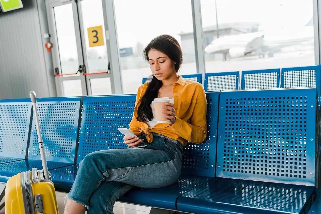 una mujer sentada en un aeropuerto con un vaso de caf&eacute;