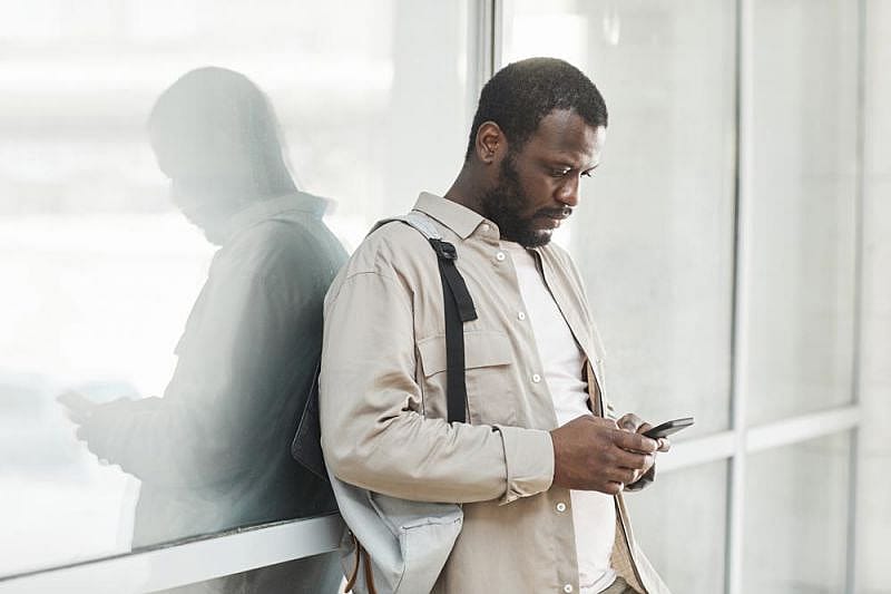 Ein Mann, der die Kundendienstrichtlinien auf seinem Handy &uuml;berpr&uuml;ft