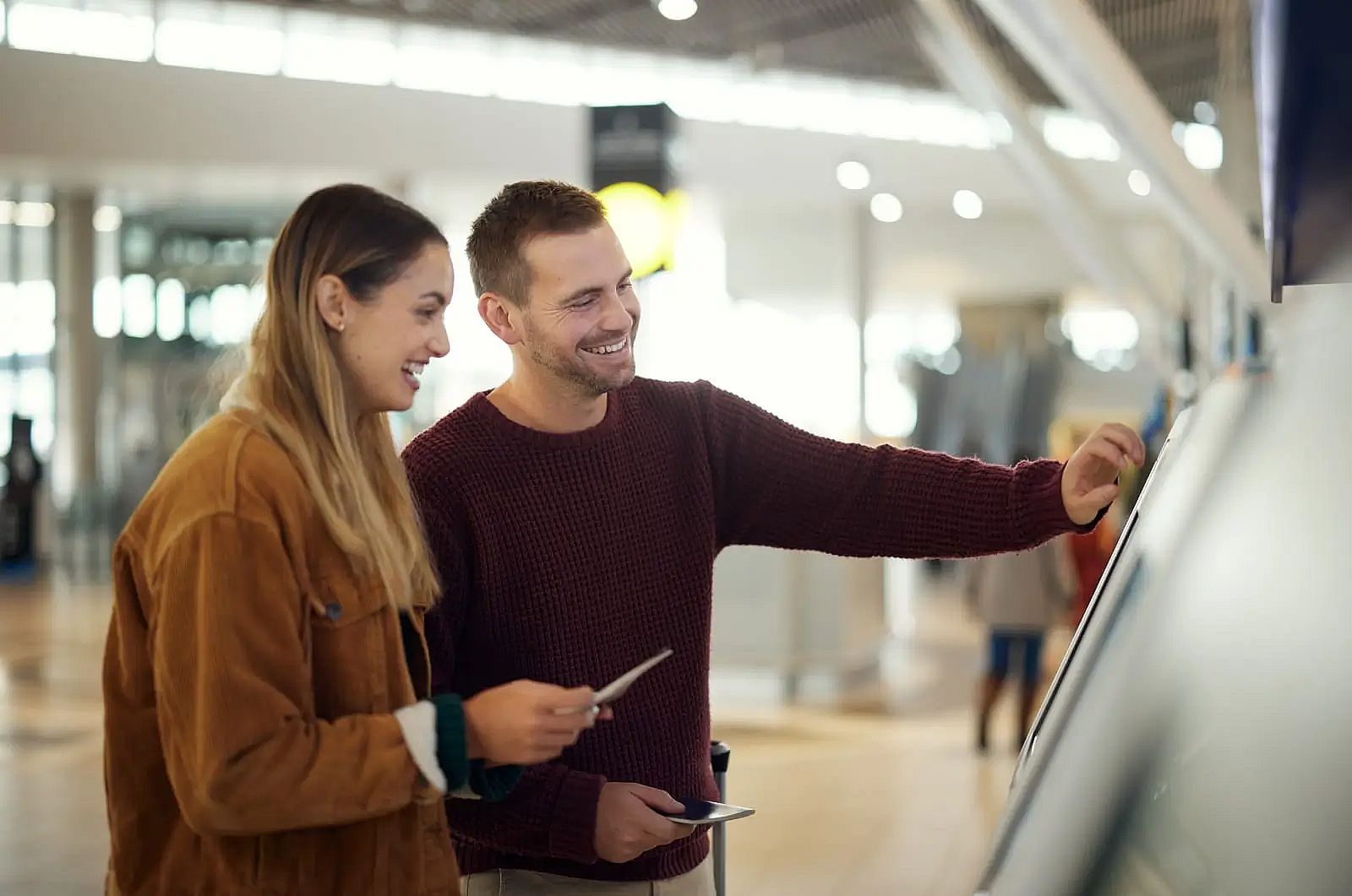 a couple in airport typing on self service screen for digital passport identity at kiosk