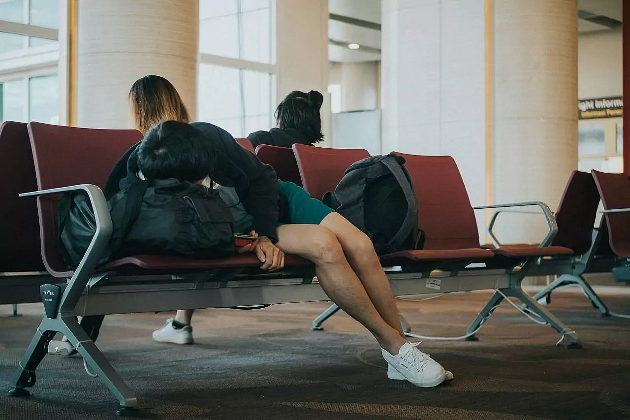 Passenger got denied boarding and sleeps on a bag at airport