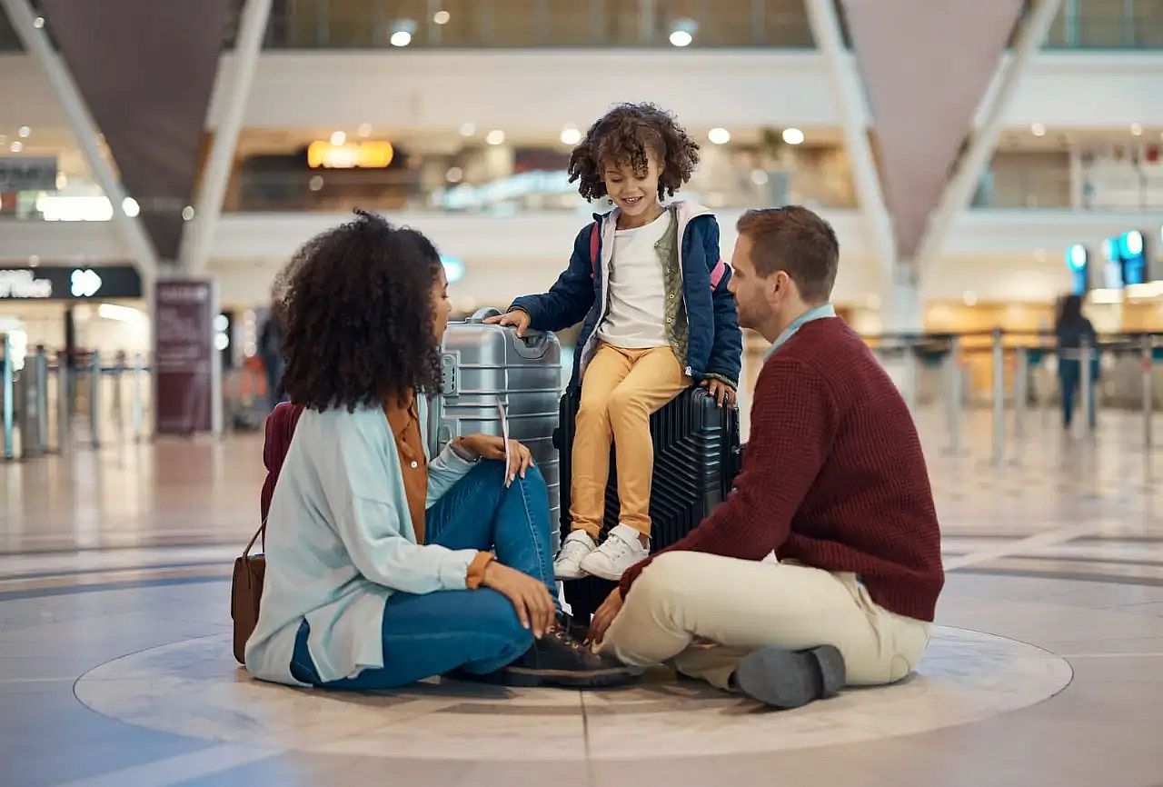 Family sitting at the airport with luggage after flight cancellation, checking refund options