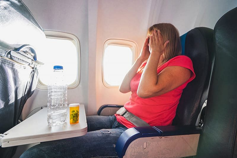 Anxious woman covering her face while flying on a plane