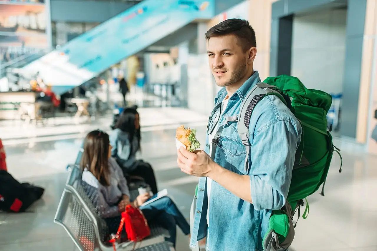 A passenger eating a sandwich while waiting at the airport