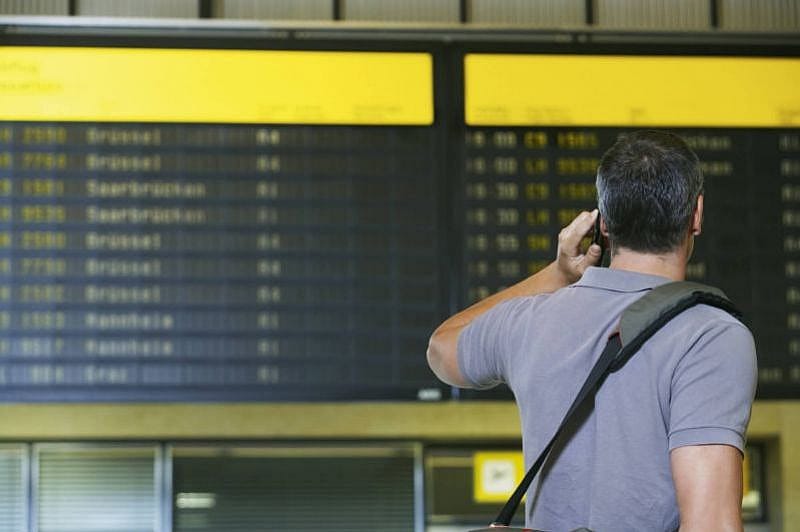Mann steht telefonierend am Flughafen