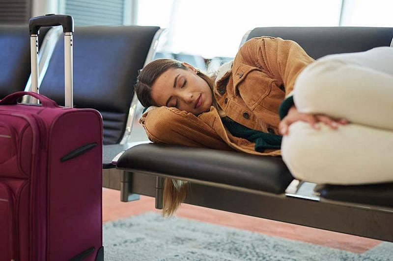 Mujer joven con maletas duerme en sala de espera de aeropuerto por retraso de vuelos de Aerol&iacute;neas Argentinas