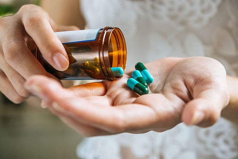 Mujer con medicinas en la mano pensando si llevar pastillas en el avi&oacute;n