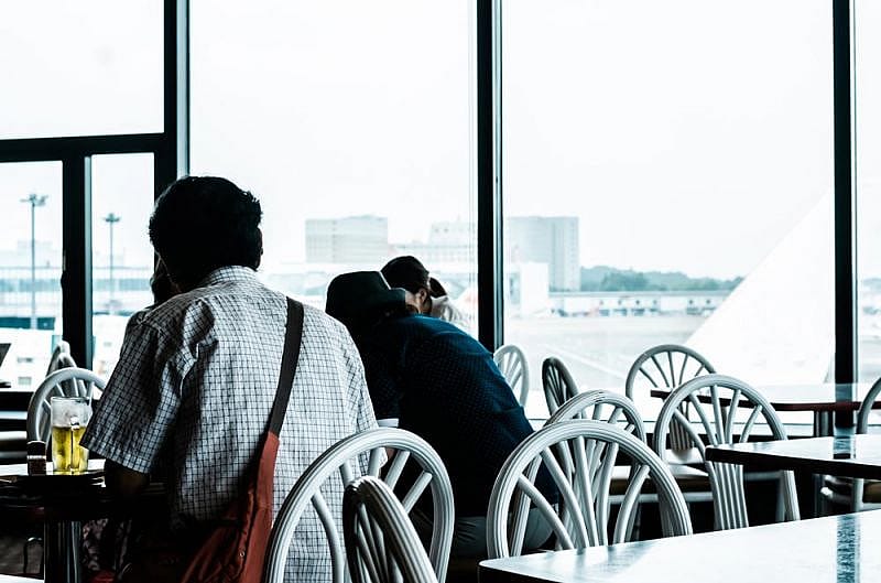 Passengers wait in an airport after Cathay Pacific cancelled their flights