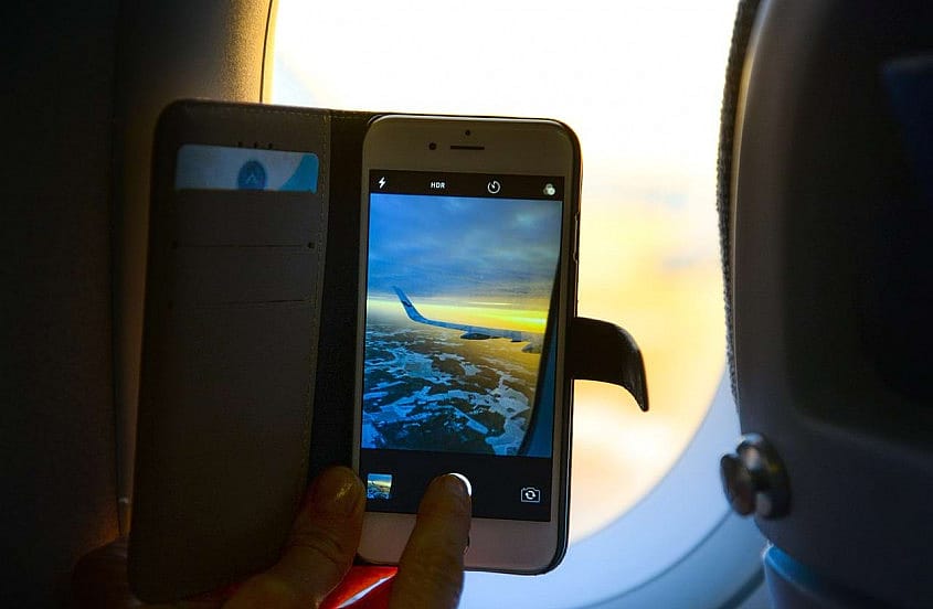 Genrebild &ouml;ver en resen&auml;r som fotar vingen p&aring; ett flygplan med sin mobiltelefon
