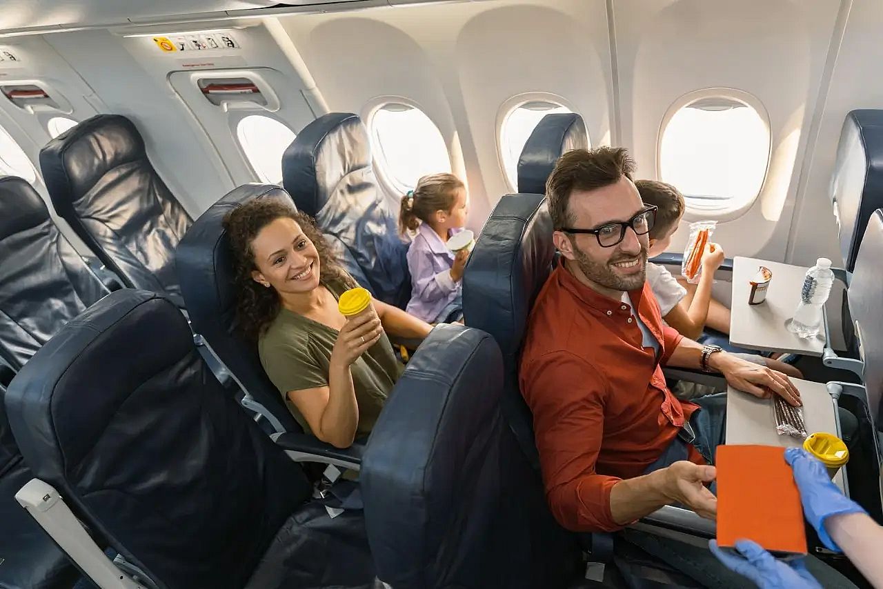 Stewardess in protective gloves giving lunch box to a passenger