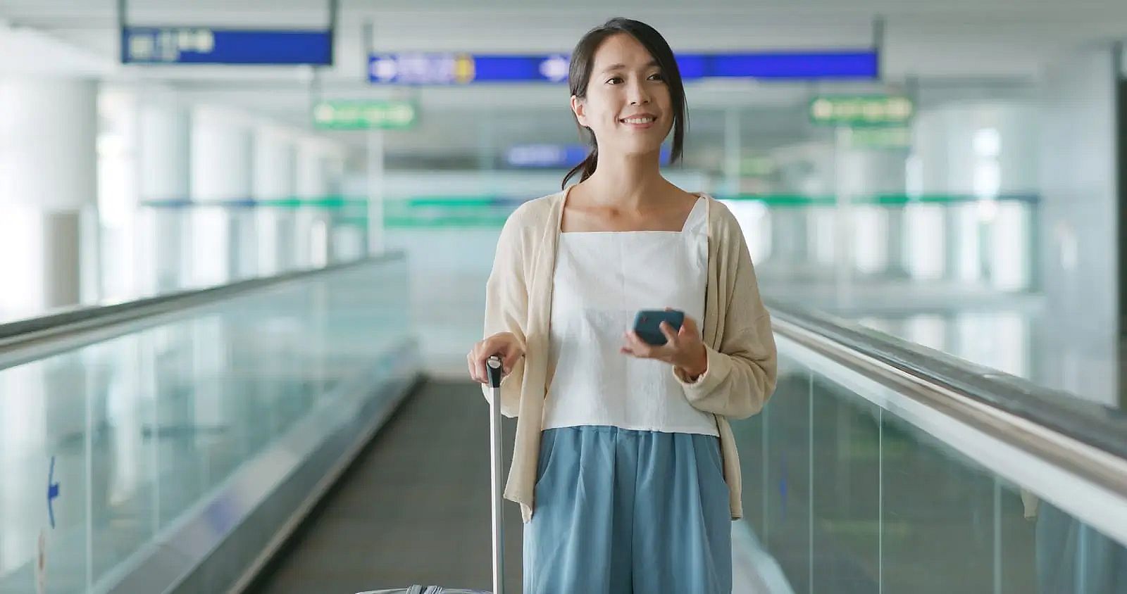 Woman in an airport checking her phone after missing a Qatar Airways flight