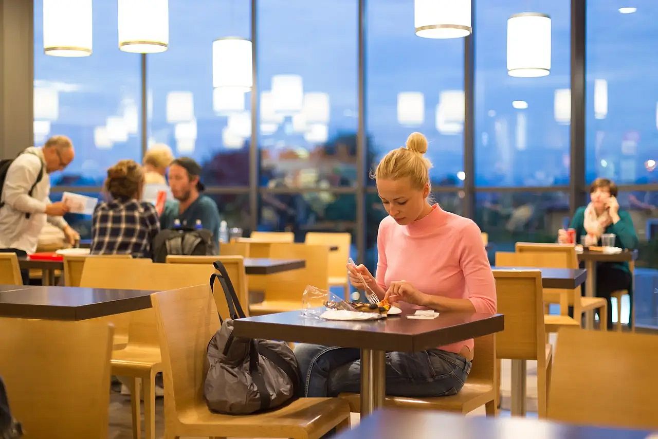a woman eating pizza while waiting for her flight