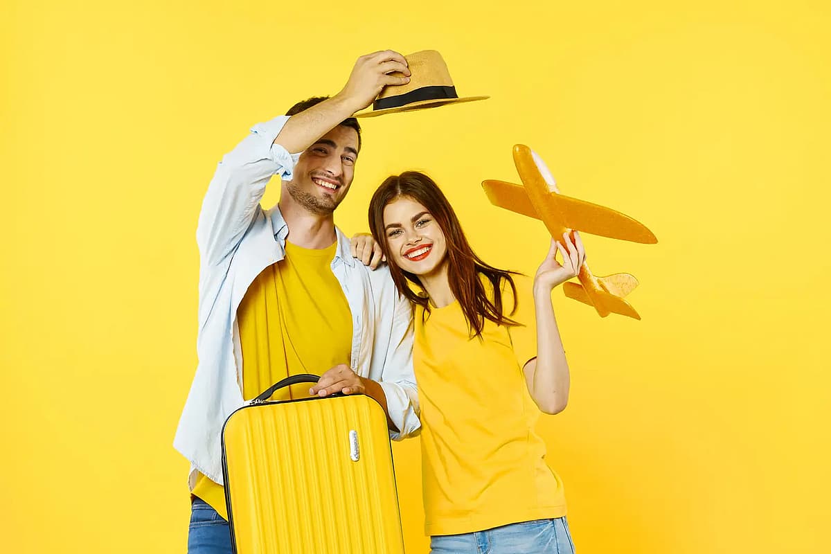 um casal com uma mala amarela e um avi&atilde;o de brincar