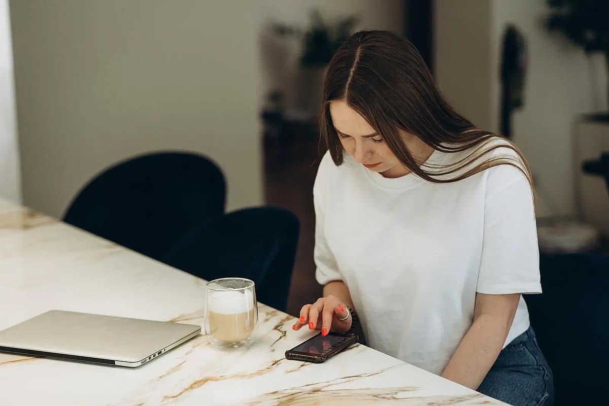en sittande kvinna som tittar p&aring; sin telefon