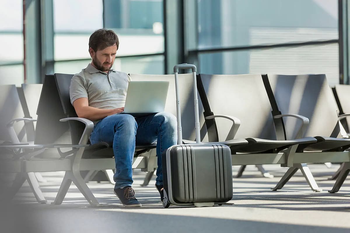uomo che lavora con il suo laptop mentre aspetta l'imbarco in aeroporto