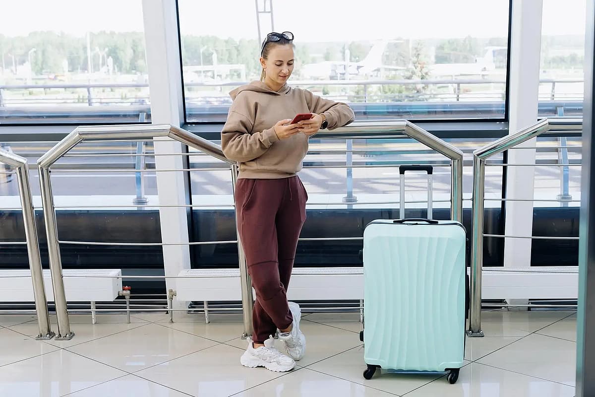 Frau liest eine SMS, w&auml;hrend sie am Flughafen steht