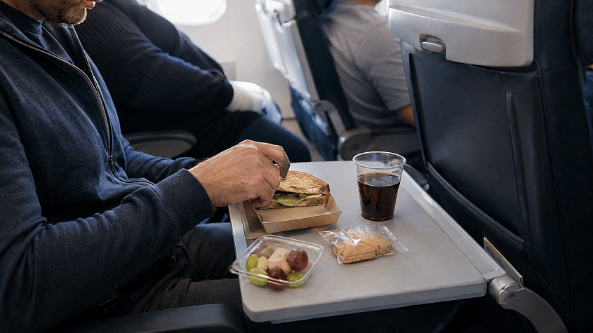 putnik jede obrok u avionu